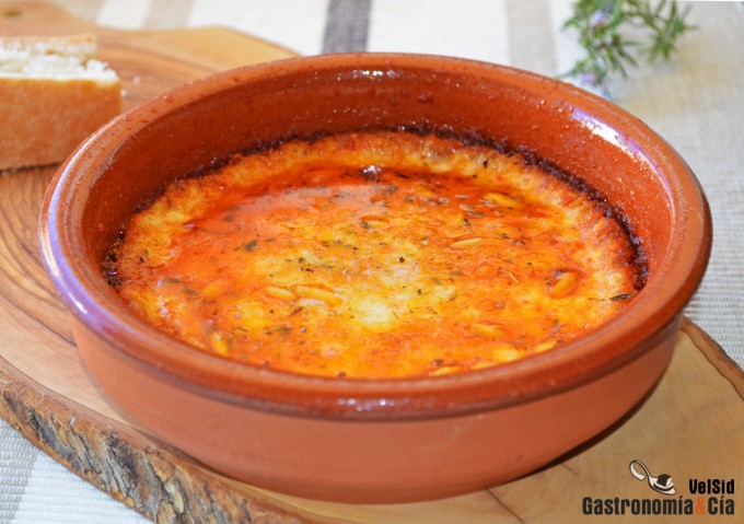 Provolone fundido con tomate, ajo asado y piñones